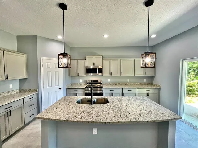 a kitchen with kitchen island granite countertop a sink a counter top space appliances and cabinets