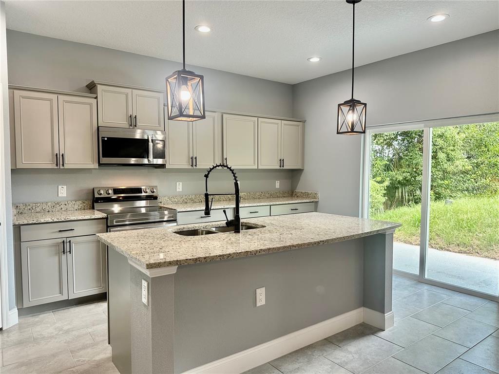 314 15th Avenue Ocoee, FL 34761 - Photo 7 of 37 a kitchen with kitchen island granite countertop a sink a counter top space appliances and cabinets