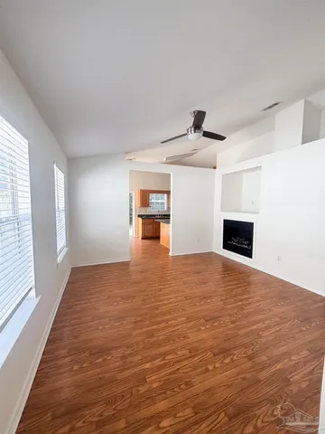 a view of empty room with wooden floor and window