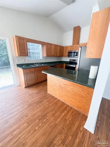 a kitchen with stainless steel appliances wooden floors and wooden cabinets