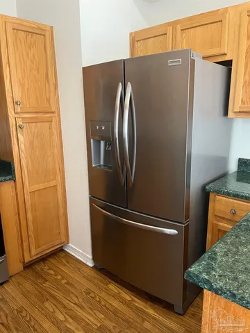 a view of a refrigerator in kitchen and an empty room