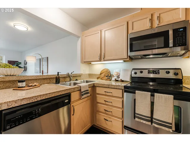 a kitchen with stainless steel appliances a stove a sink dishwasher and cabinets with wooden floor