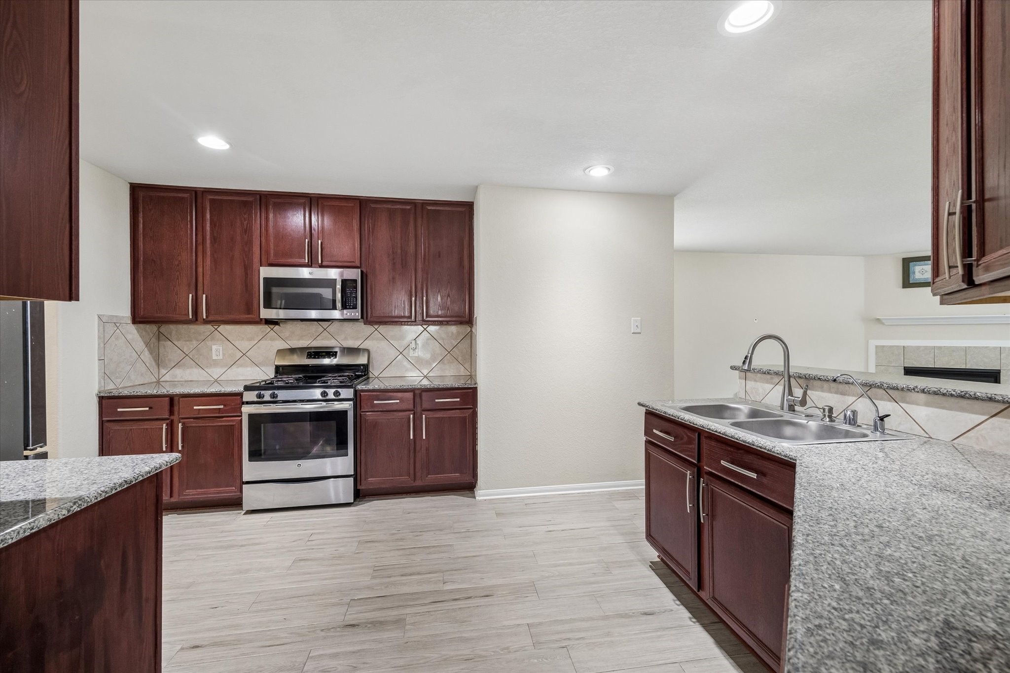 15642 South Fall Fern Circle Houston, TX 77044 - Photo 12 of 25 a kitchen with stainless steel appliances granite countertop a sink stove microwave and refrigerator