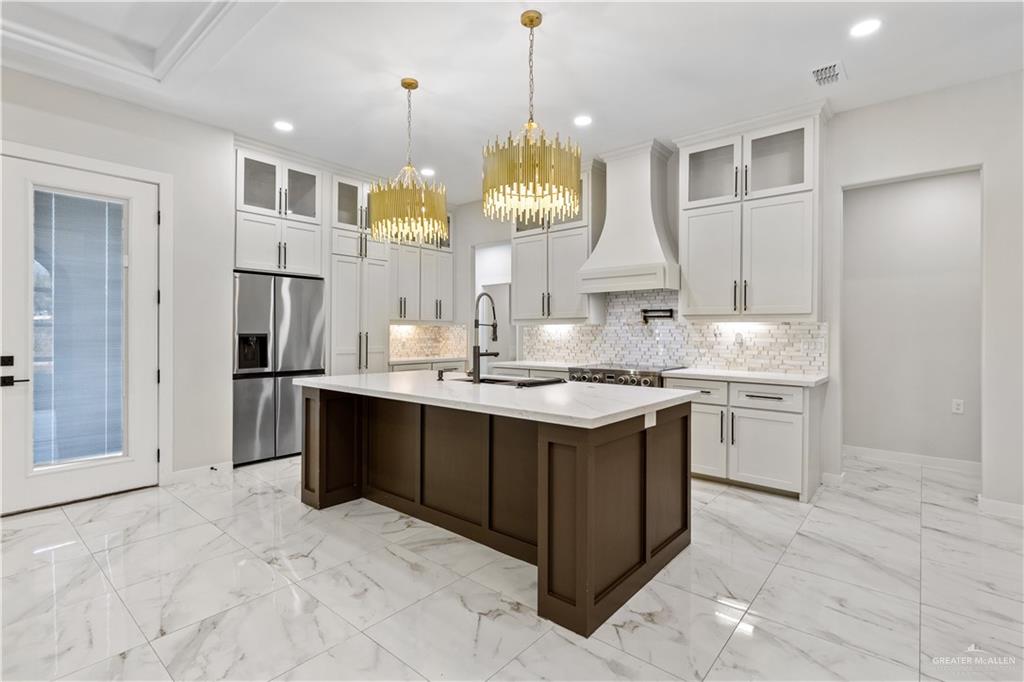 3509 Astrid Street Mission, TX 78574 - Photo 12 of 30 a kitchen with kitchen island granite countertop a stove a sink a refrigerator and a chandelier