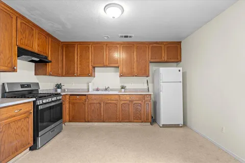 a kitchen with granite countertop a sink stove and refrigerator