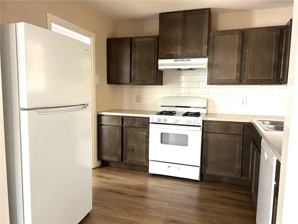 a white refrigerator freezer sitting inside of a kitchen with stainless steel appliances wooden floor