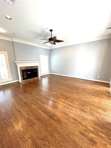 an empty room with wooden floor fireplace and windows