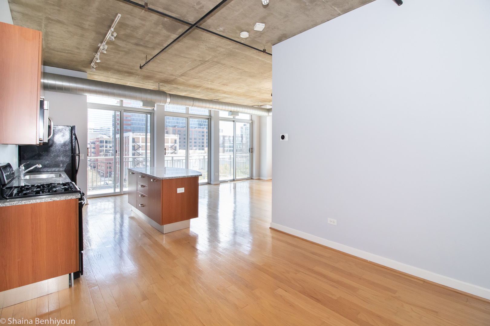 111 South Morgan Street, Unit 715 Chicago, IL 60607 - Photo 8 of 17 a open kitchen with granite countertop a stove top oven a sink and dishwasher with wooden floor
