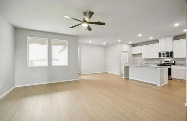 a view of kitchen with kitchen island stainless steel appliances wooden floor cabinets and a window