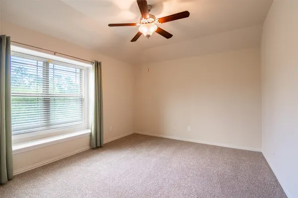 an empty room with a window and a fan