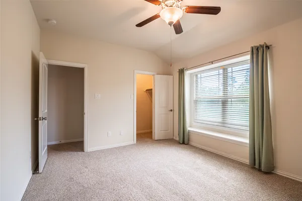 an empty room with hallway closet and chandelier fan