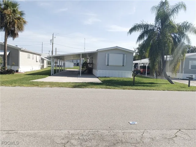 a view of a house with a yard and palm trees