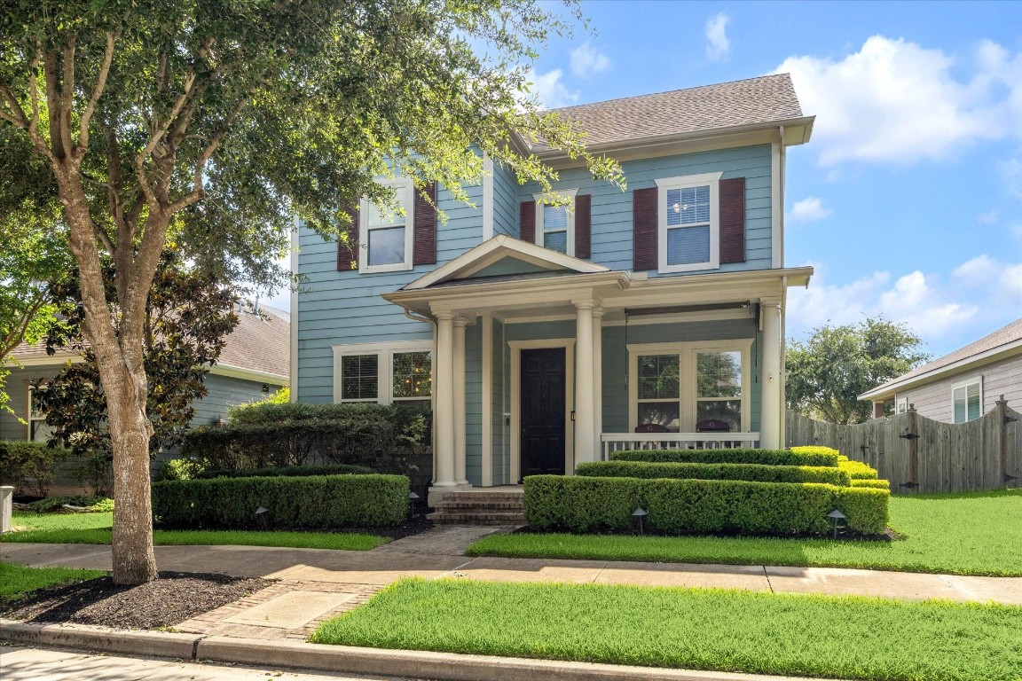 Charming two-story home with a classic design, featuring a welcoming front porch, well-maintained landscaping, and mature trees that line the street.