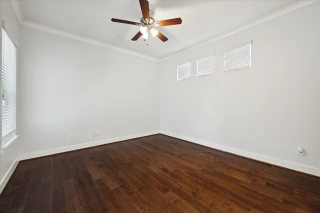 an empty room with wooden floor ceiling fan and windows