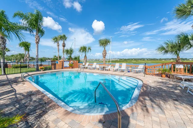 a view of a swimming pool with a lawn chairs under palm trees