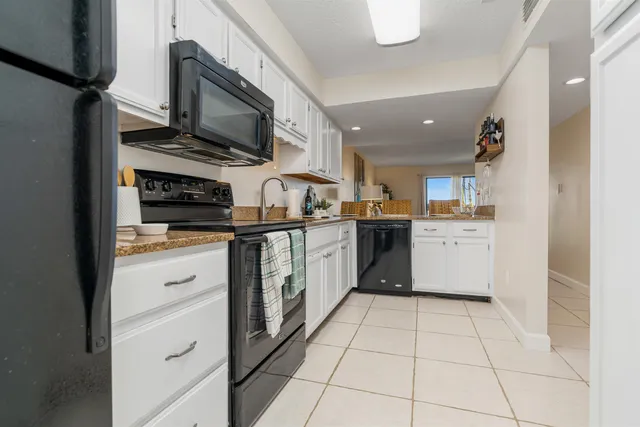 a kitchen with stainless steel appliances granite countertop a stove top oven a sink and white cabinets