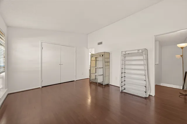 an empty room with walk in closet and wooden floor