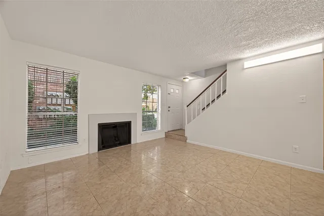 a view of an empty room with a fireplace and a window