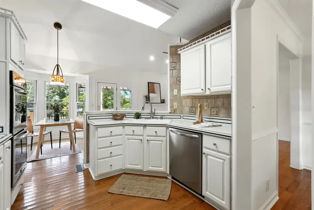 a kitchen with stainless steel appliances white cabinets a sink and a stove
