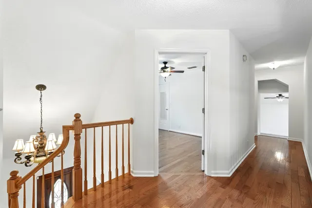 an empty room with wooden floor fan and window