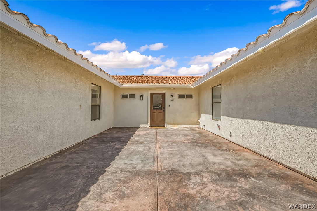 4088 Mercer Road Bullhead City, AZ 86429 - Photo 5 of 35 Spacious stucco courtyard featuring a decorative stamped concrete surface, tile roofing, and a wooden entry door