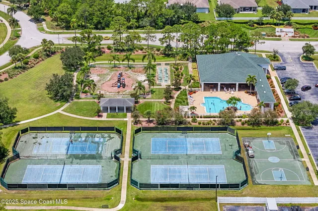 an aerial view of a house with swimming pool and large trees