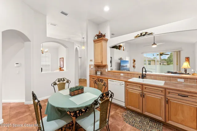 a large kitchen with a table chairs sink and cabinets