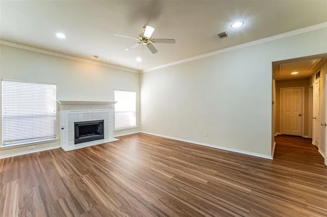 an empty room with wooden floor fireplace and windows