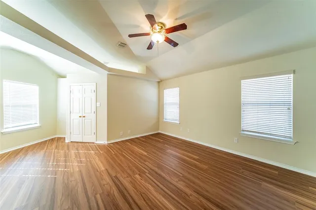 an empty room with wooden floor and windows