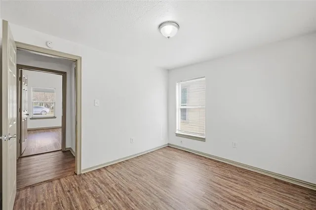a view of empty room with wooden floor and window