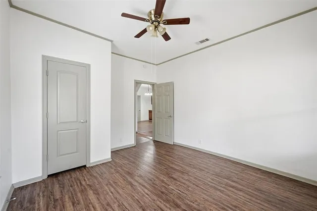 an empty room with wooden floor ceiling fan and windows