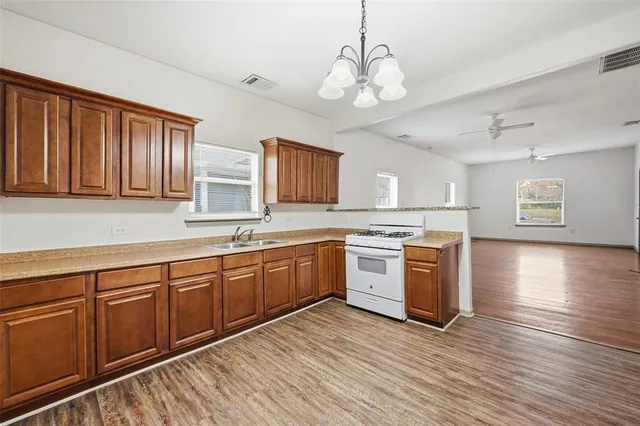 a large kitchen with stainless steel appliances granite countertop a sink dishwasher stove and wooden floor