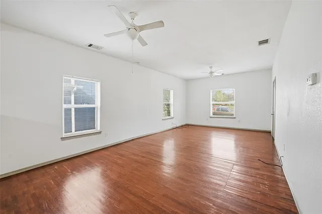 a view of an empty room with a window and wooden floor