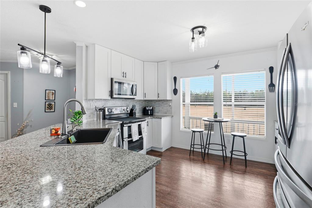 952 Gallilee Loop Lake City, FL 32024 - Photo 12 of 60 a kitchen with stainless steel appliances granite countertop a refrigerator a sink dishwasher a stove and white cabinets with wooden floor