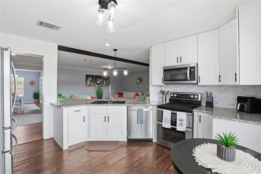 952 Gallilee Loop Lake City, FL 32024 - Photo 13 of 60 a kitchen with stainless steel appliances kitchen island granite countertop a stove a sink and a white cabinets