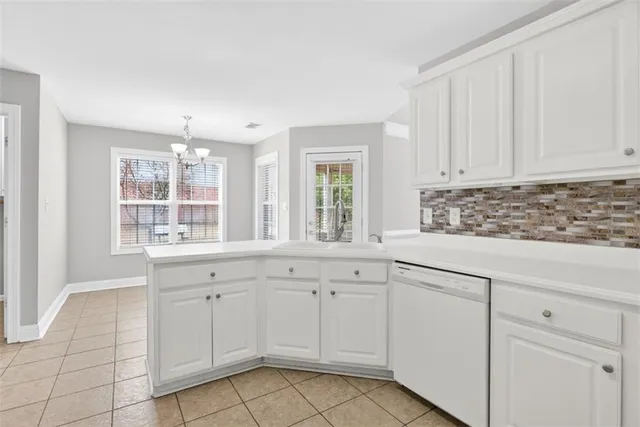 a kitchen with white cabinets appliances a sink and a window