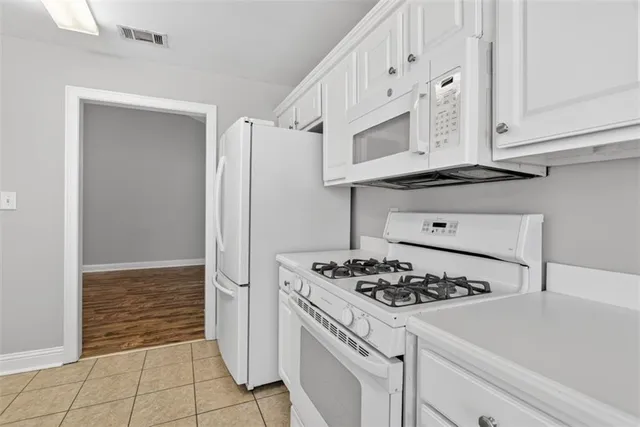 a kitchen with white cabinets and appliances