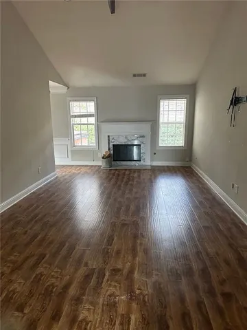 an empty room with wooden floor fireplace and windows