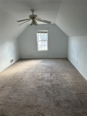 an empty room with a chandelier fan and windows