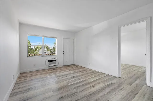 a view of an empty room with a window and wooden floor