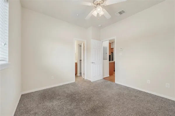an empty room with a chandelier fan and closet