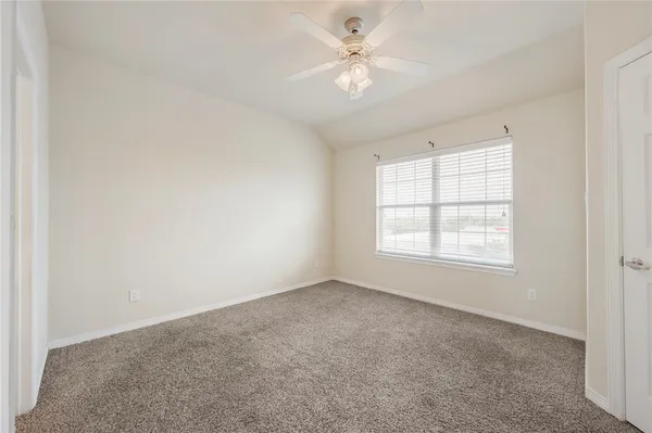 an empty room with chandelier fan and windows