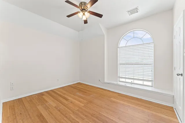 an empty room with windows and fan