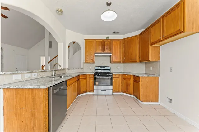 a kitchen with granite countertop a sink stainless steel appliances and cabinets