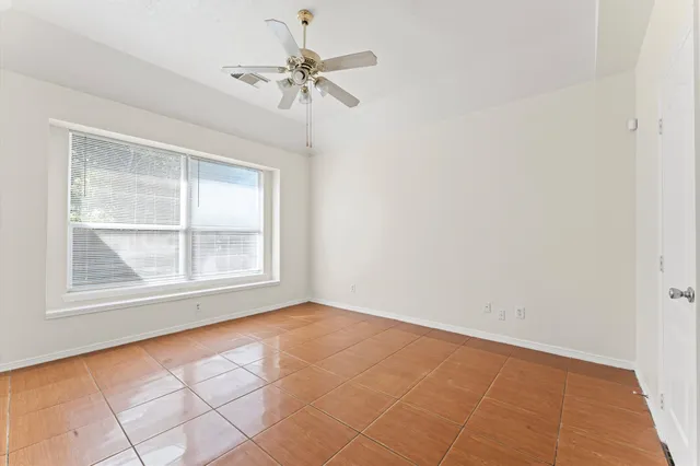 an empty room with a chandelier fan and windows