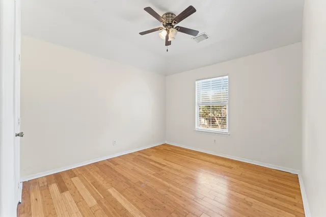 a view of a big room with wooden floor and a chandelier fan