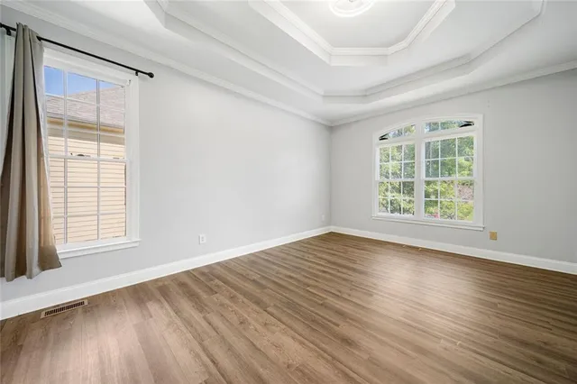 an empty room with wooden floor and windows