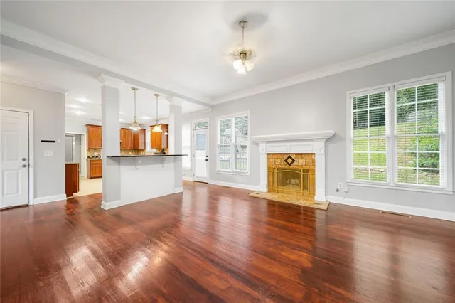 a view of an empty room with a window and wooden floor