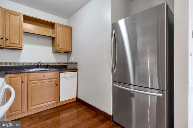 a kitchen with stainless steel appliances granite countertop a refrigerator a sink and white cabinets