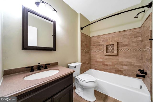 a bathroom with a granite countertop sink a toilet a mirror and shower